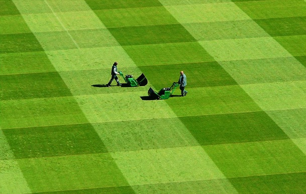 2 jardineros cortando el césped del estadio olímpico de Pekín